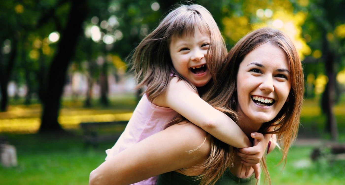 Mother giving piggyback ride to daughter with special needs