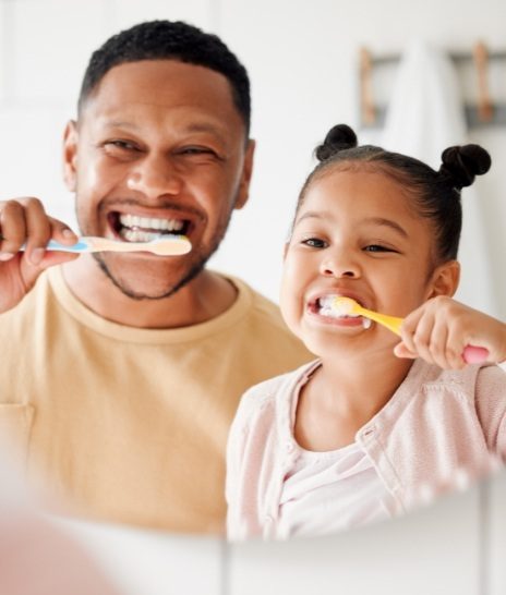 Father and daughter brushing their teeth together