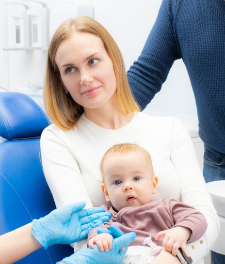 Mother sitting in dental chair with baby in her lap