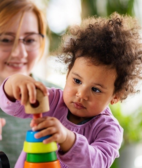 Toddler playing with stack of wooden ring toys