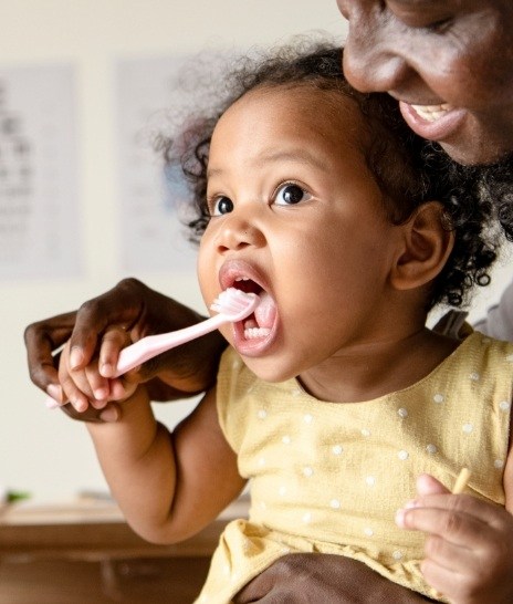 Parent helping their toddler brush their teeth