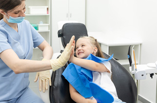 Little blond girl high-fiving dentist