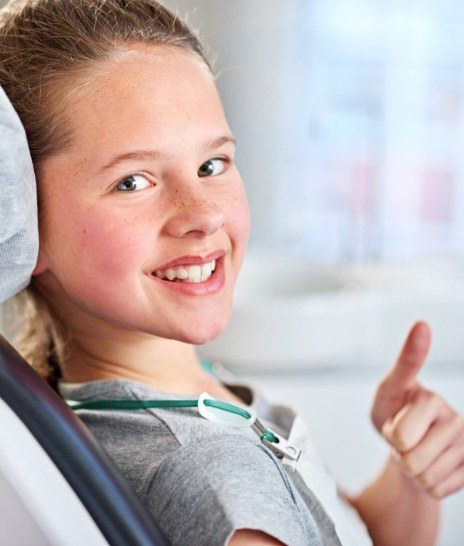 Child giving thumbs up in dental chair
