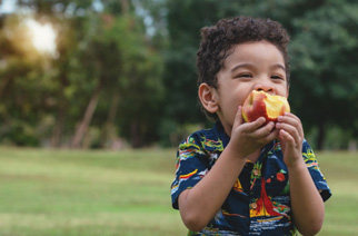 Child eating piece of fruit at the park