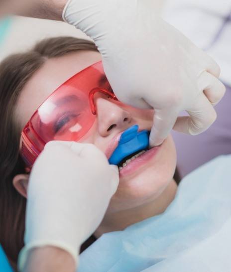 Girl in dental chair with fluoride trays over her teeth