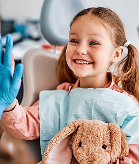 Happy young girl high-fiving dental team member