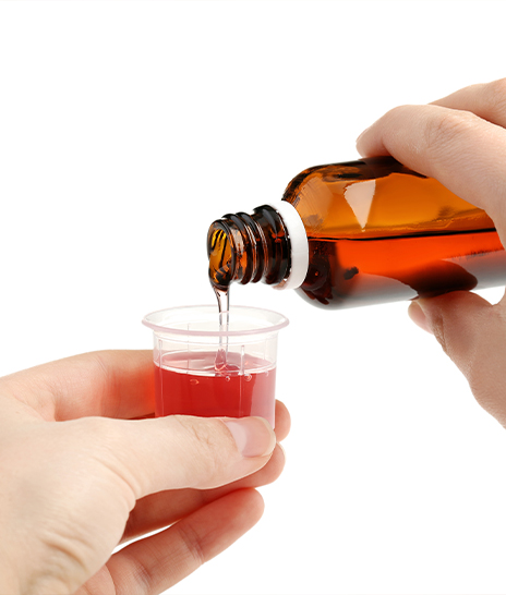 Person pouring liquid medicine into cap