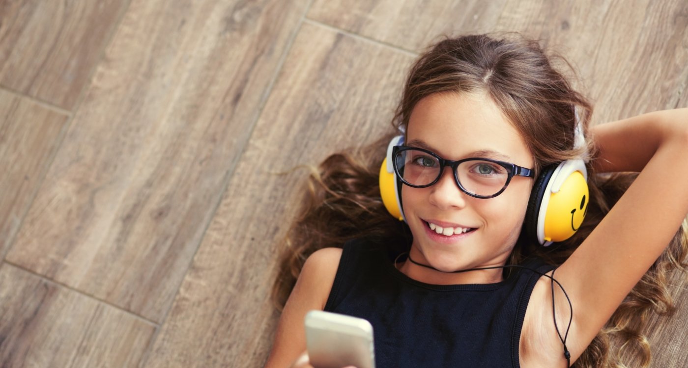 Young girl wearing headphones and smiling after pediatric dental services in Fort Worth