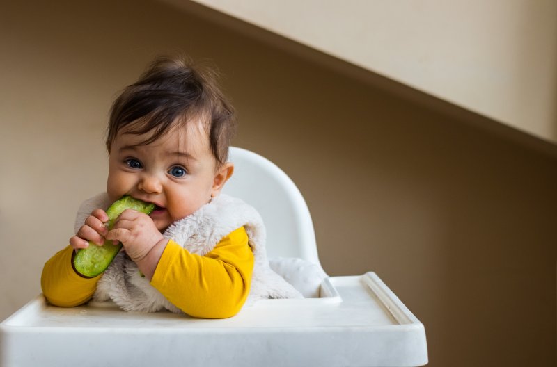 baby trying to eat a vegetable