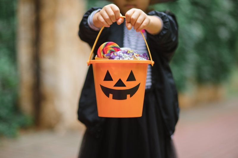 child holding a Halloween bucket of candy